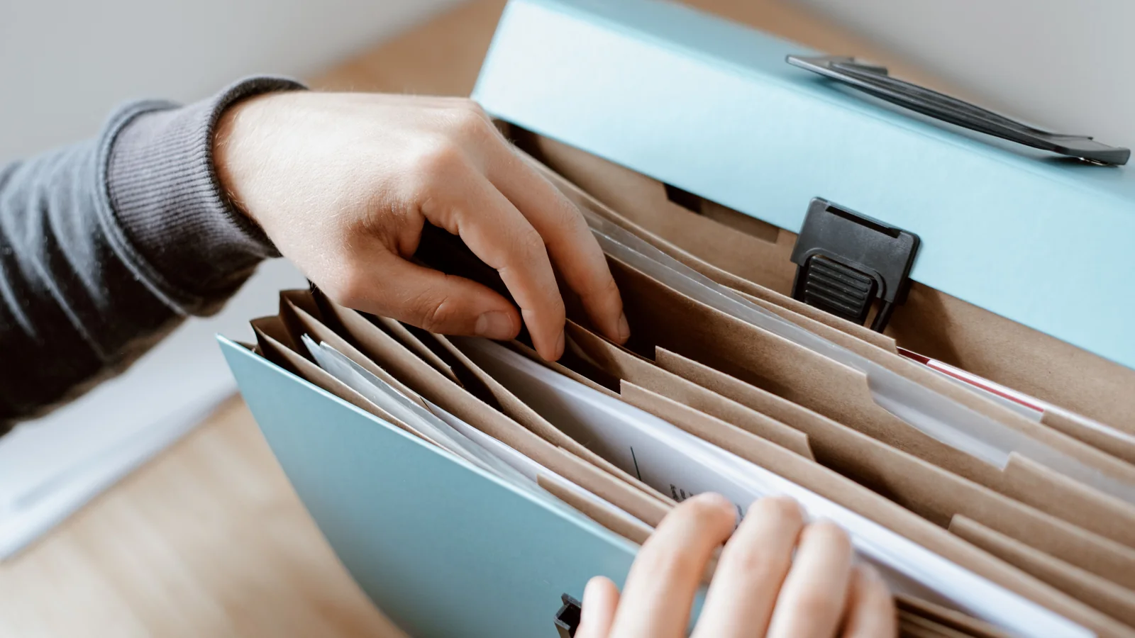 Hands organising paper documents in a folder to represent arranging PDF pages