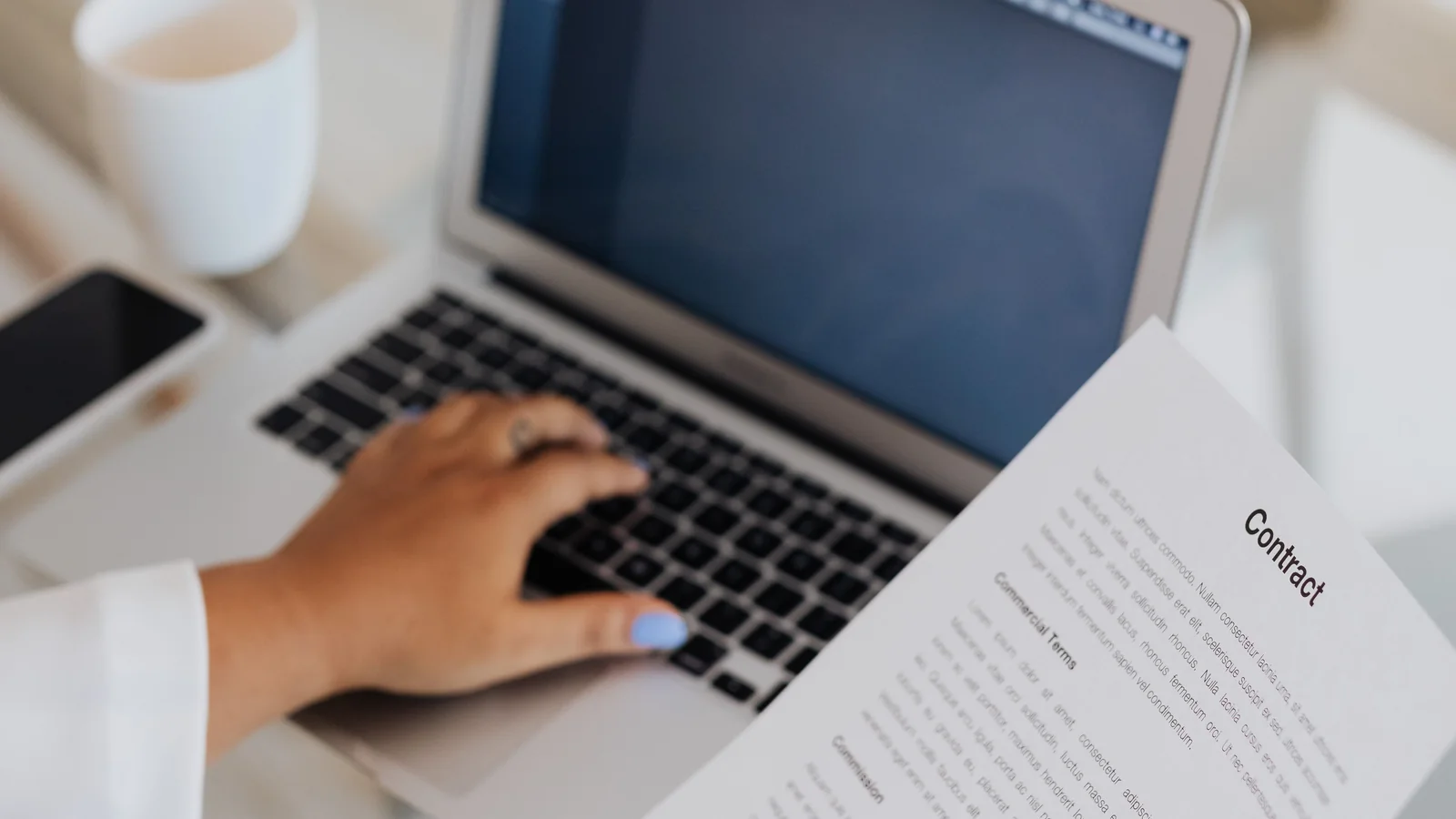 Person reviewing a document beside a laptop while choosing the right PDF tool